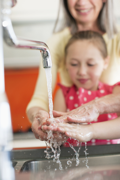 Grandmother helping granddaughter to wash her hands